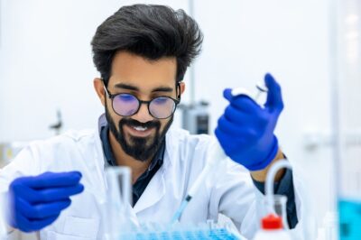 Man scientist wearing protective gloves dripping chemicals to test tubes, biochemist conducting experiments to discover new drugs, working in science lab.